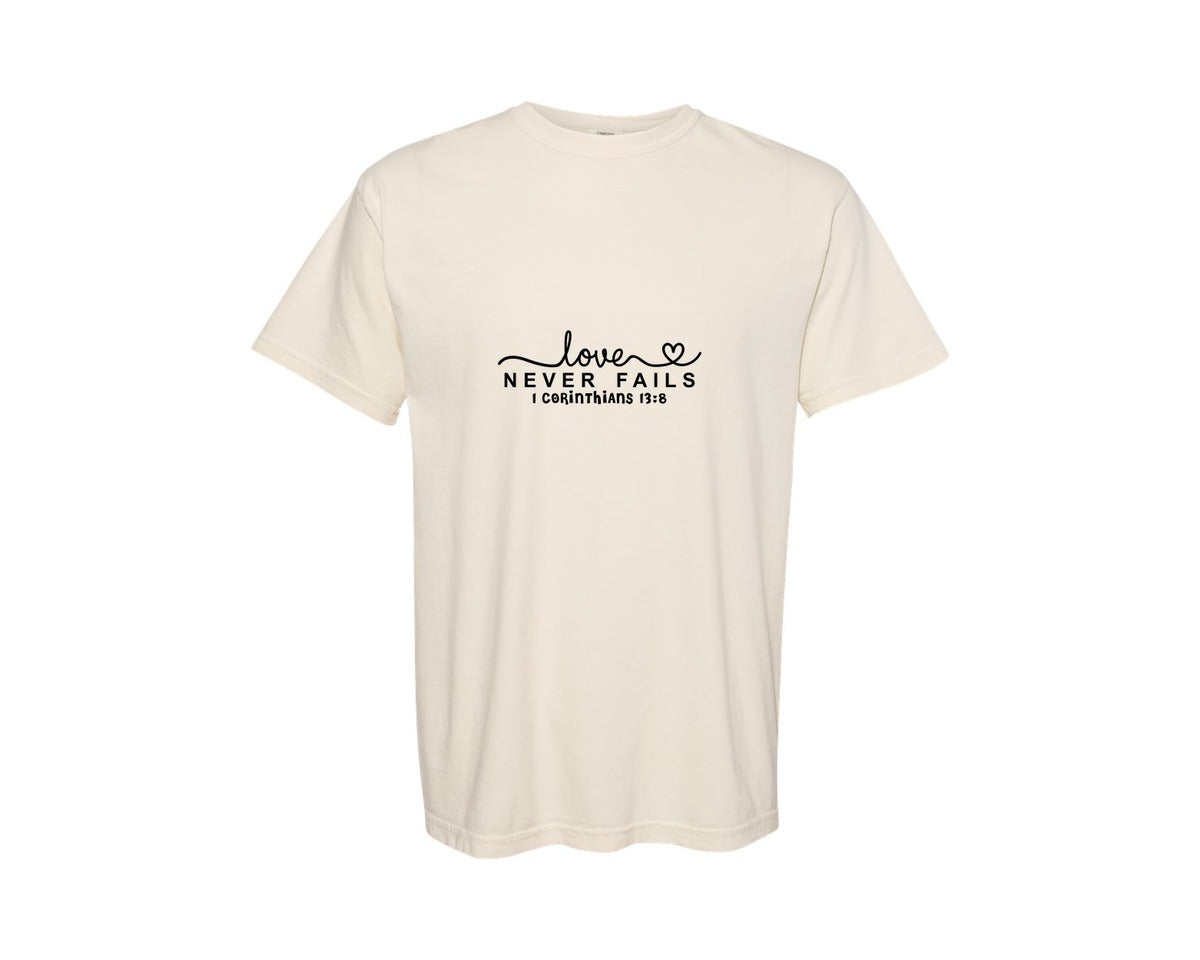 brand:Comfort Colors|color:Ivory|Love Never Fails Svgvalentine Faith Graphic T-Shirt