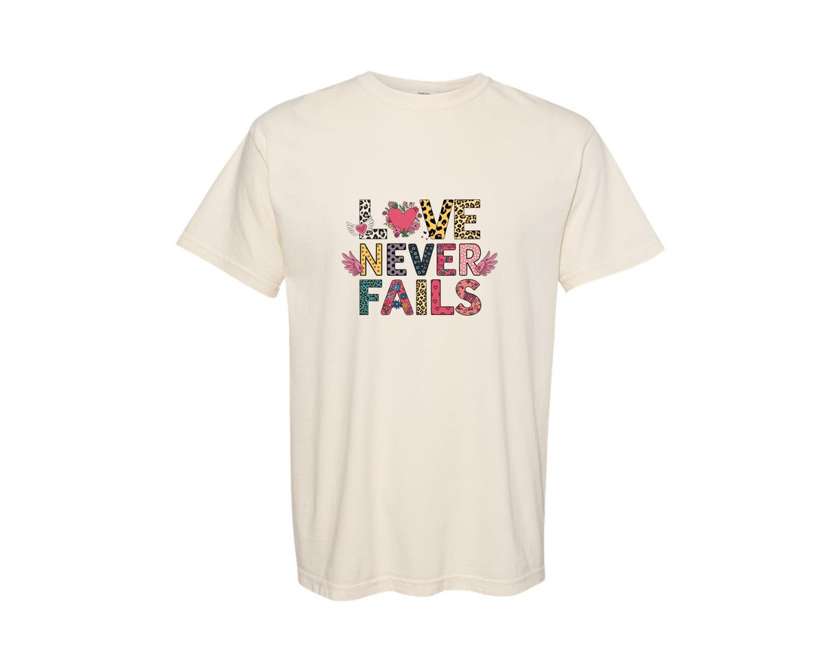 brand:Comfort Colors|color:Ivory|Love Never Fails Trendy Valentines Graphic T-Shirt