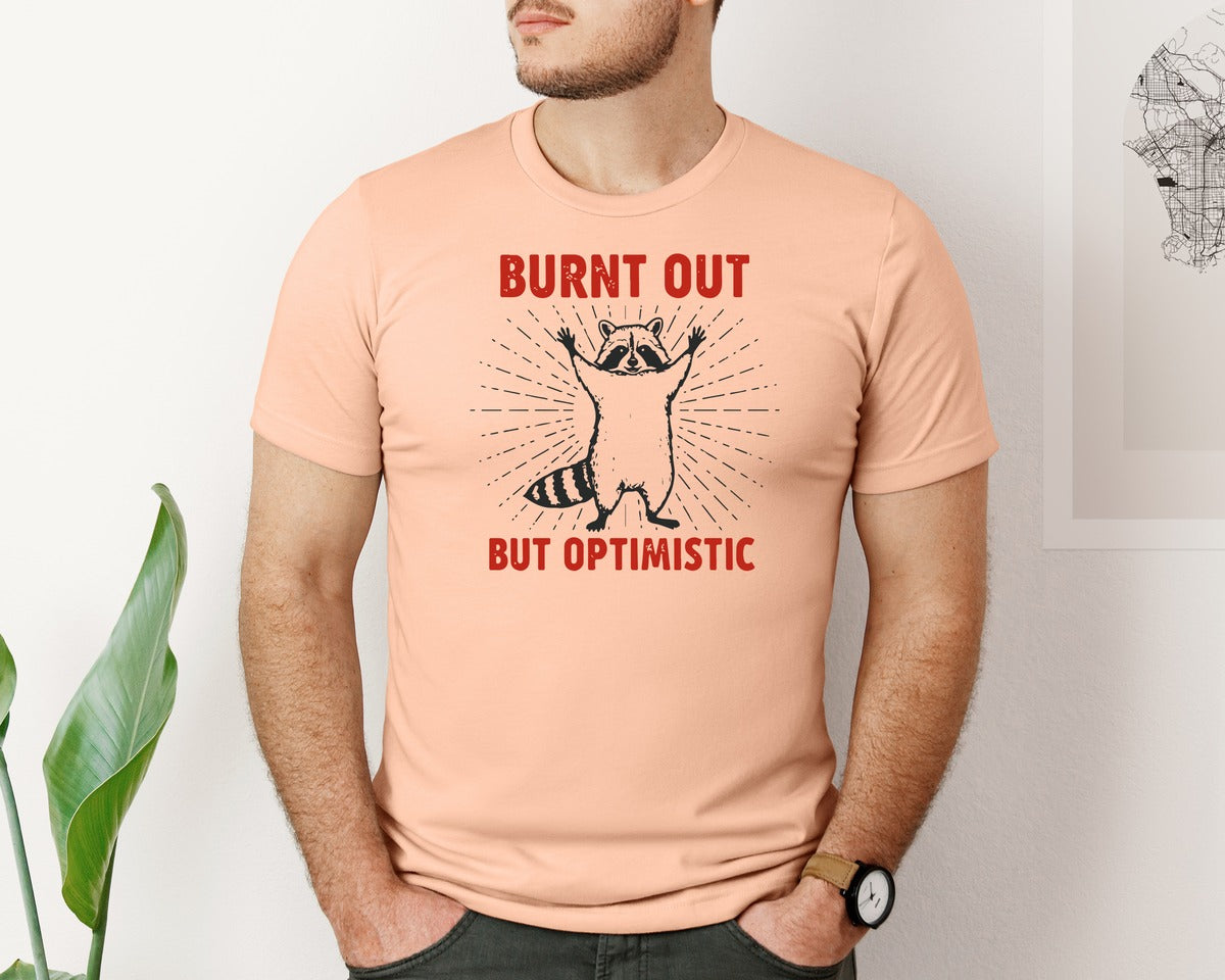 brand:Bella Canvas|color:Heather Peach|Burnt Out But Optimistic Raccoon Graphic T-Shirt