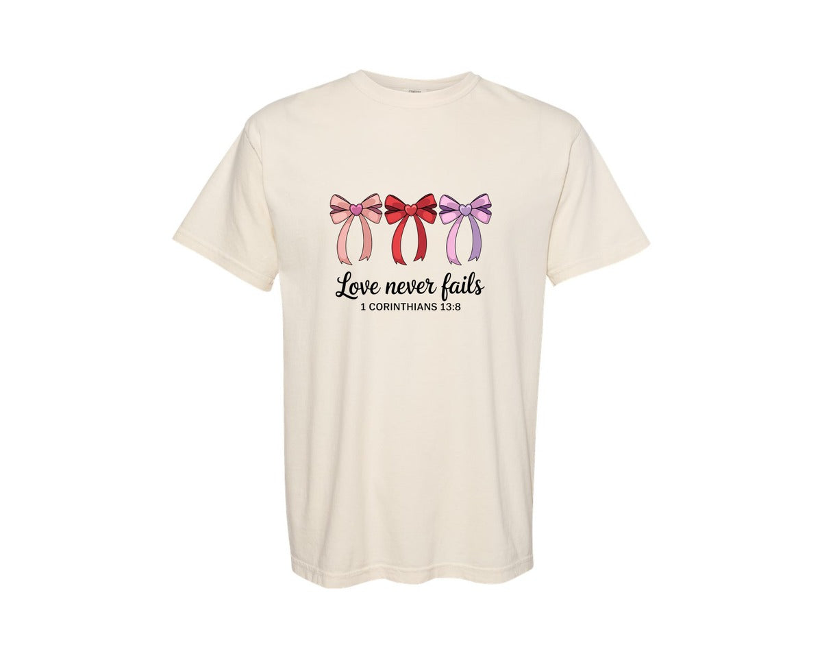 brand:Comfort Colors|color:Ivory|Love Never Fails Bible Verse Coquet Graphic T-Shirt