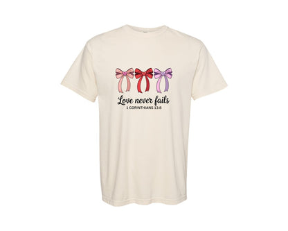 brand:Comfort Colors|color:Ivory|Love Never Fails Bible Verse Coquet Graphic T-Shirt