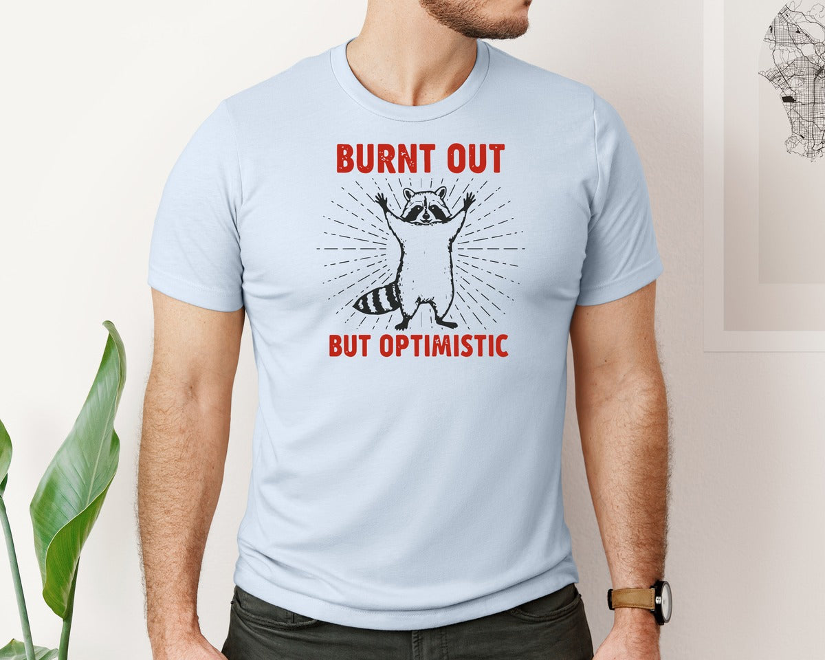 brand:Bella Canvas|color:Light Blue|Burnt Out But Optimistic Raccoon Graphic T-Shirt