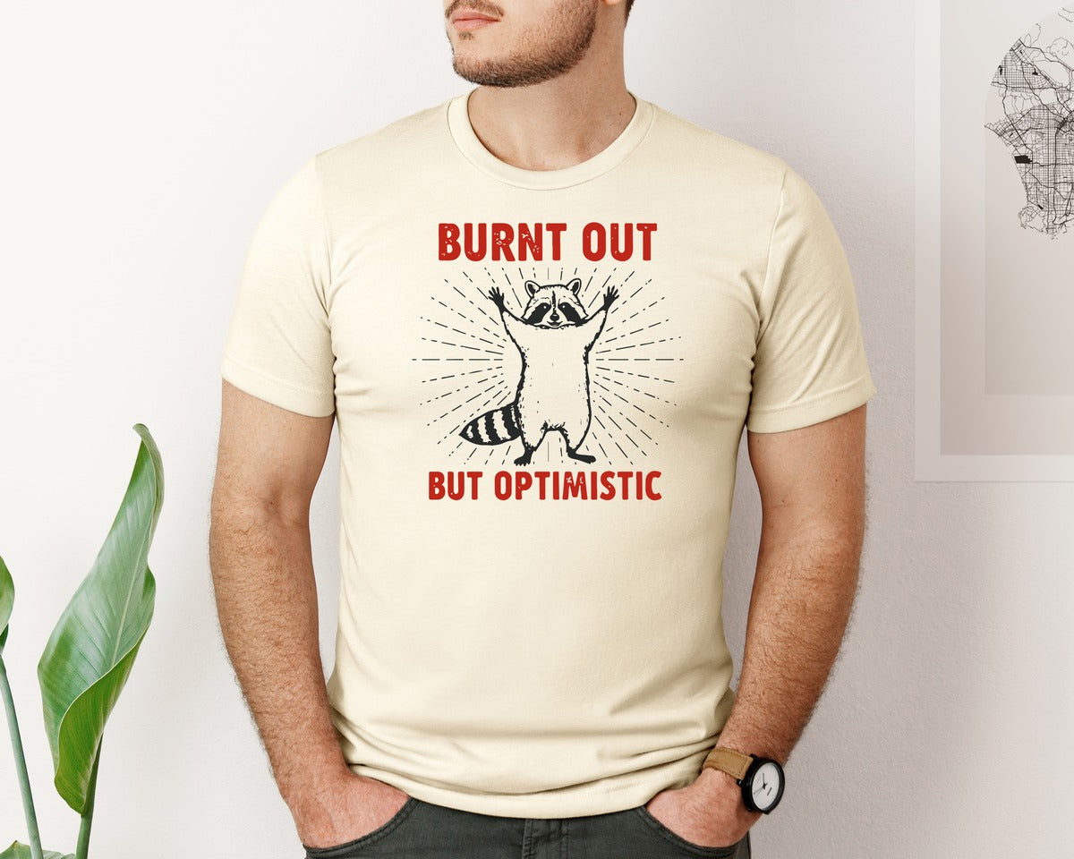 brand:Bella Canvas|color:Light Cream / Natural|Burnt Out But Optimistic Raccoon Graphic T-Shirt