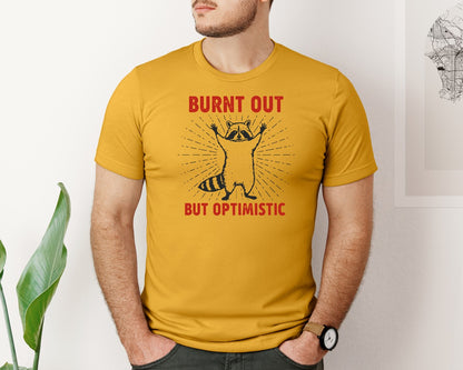 brand:Bella Canvas|color:Mustard|Burnt Out But Optimistic Raccoon Graphic T-Shirt