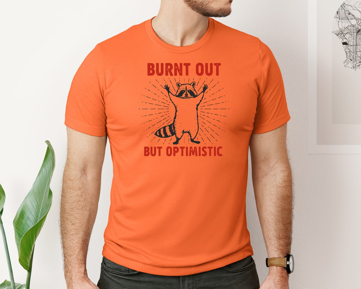 brand:Bella Canvas|color:Orange|Burnt Out But Optimistic Raccoon Graphic T-Shirt