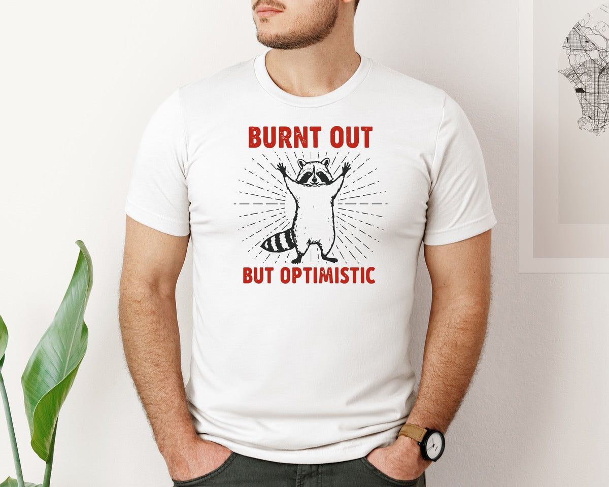 brand:Bella Canvas|color:White|Burnt Out But Optimistic Raccoon Graphic T-Shirt
