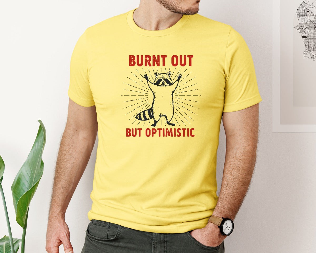 brand:Bella Canvas|color:Yellow|Burnt Out But Optimistic Raccoon Graphic T-Shirt